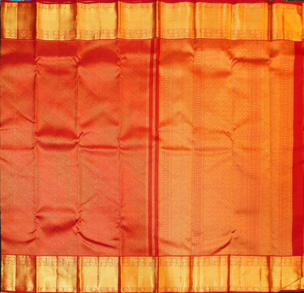 A close-up of a richly colored fabric, likely a sari, featuring a dominant redbody with a golden-yellow border and subtle woven patterns.