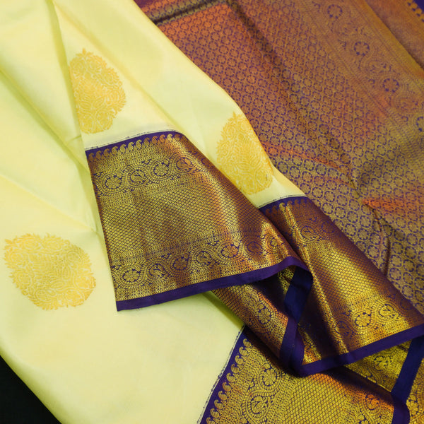 Lemon yellow vintage Kanchipuram silk saree with navy blue korvai border, featuring gold floral thilagam motifs on the body and a richly woven traditional zari pallu.