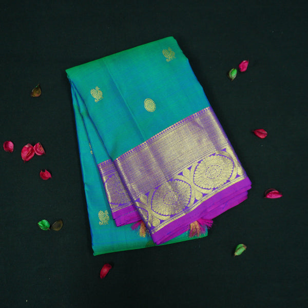 Peacock blue Kanchipuram silk saree with violet border, gold zari peacock and chakaram butta, and rich woven pallu – traditional bridal saree by Vivaaha Silks.