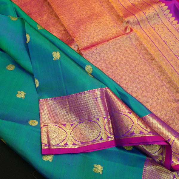 Peacock blue Kanchipuram silk saree with violet border, gold zari peacock and chakaram butta, and rich woven pallu – traditional bridal saree by Vivaaha Silks.