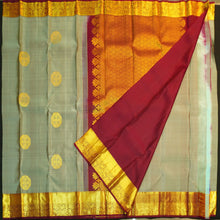 Load image into Gallery viewer, Grey Kanchipuram silk saree with gold zari chakaram butta, rich orange-gold pallu, and brown floral border – traditional wedding silk saree from Vivaaha Silks.