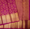 A close-up of a rich magenta pink and gold Banarasi silk saree, showcasing its floral zari embroidery, detailed border patterns, and metallic gold weave.