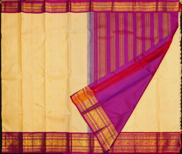 A cream-colored silk saree with a rich magenta purple border and gold zari metallic patterns, shown with the pallu folded over.