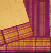 A close-up of a traditional Indian silk saree, showing a light beige body with subtle gold motifs, a rich magenta-purple border, and intricate gold zari brocade work.