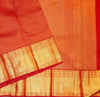 A close-up of a redsilk saree with intricate gold zari woven borders and patterns.