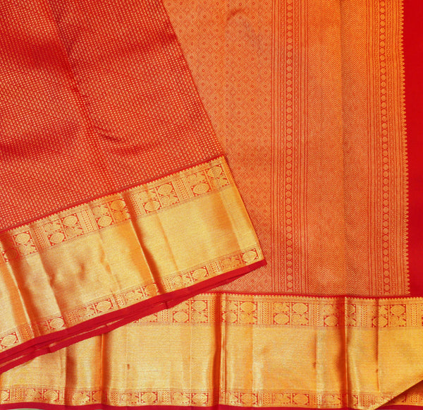A close-up of a redsilk saree with intricate gold zari woven borders and patterns.