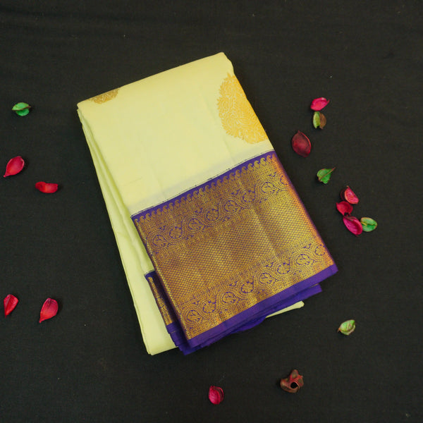 Lemon yellow vintage Kanchipuram silk saree with navy blue korvai border, featuring gold floral thilagam motifs on the body and a richly woven traditional zari pallu.