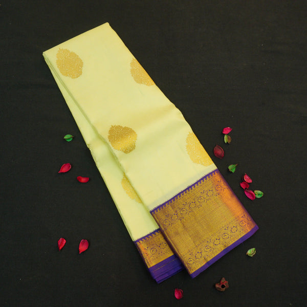 Lemon yellow vintage Kanchipuram silk saree with navy blue korvai border, featuring gold floral thilagam motifs on the body and a richly woven traditional zari pallu.