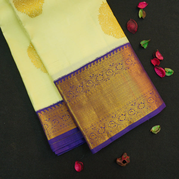 Lemon yellow vintage Kanchipuram silk saree with navy blue korvai border, featuring gold floral thilagam motifs on the body and a richly woven traditional zari pallu.