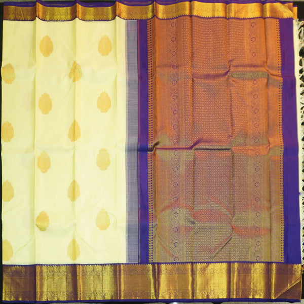 Lemon yellow vintage Kanchipuram silk saree with navy blue korvai border, featuring gold floral thilagam motifs on the body and a richly woven traditional zari pallu.