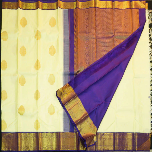 Lemon yellow vintage Kanchipuram silk saree with navy blue korvai border, featuring gold floral thilagam motifs on the body and a richly woven traditional zari pallu.