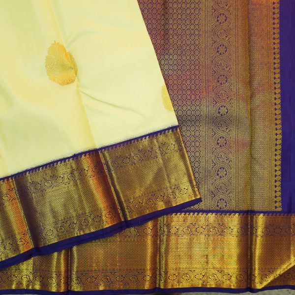 Lemon yellow vintage Kanchipuram silk saree with navy blue korvai border, featuring gold floral thilagam motifs on the body and a richly woven traditional zari pallu.