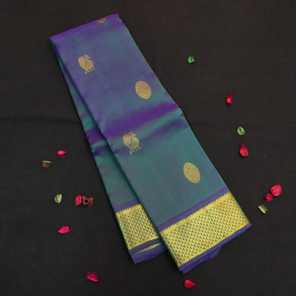 Peacock blue Kanchipuram silk saree from Vivaaha Silks budget collection featuring gold annam and chakaram butta, and a grand zari pallu with paisley and diamond motifs.